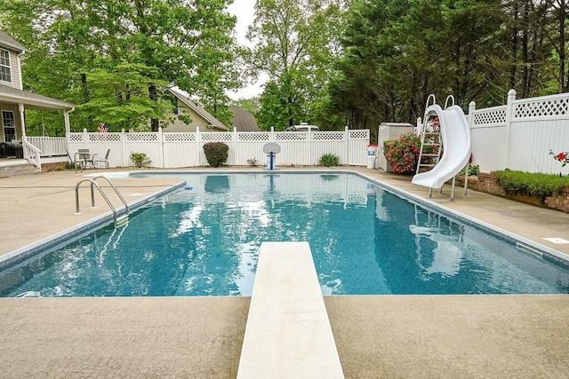 view of swimming pool featuring a fenced backyard, a diving board, a fenced in pool, a water slide, and a patio area