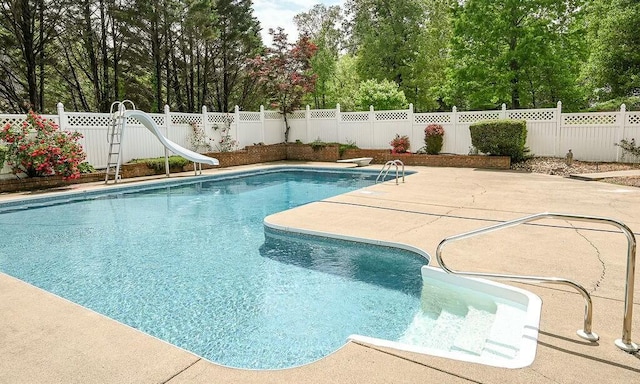 view of swimming pool with a water slide, a fenced backyard, a fenced in pool, and a patio area