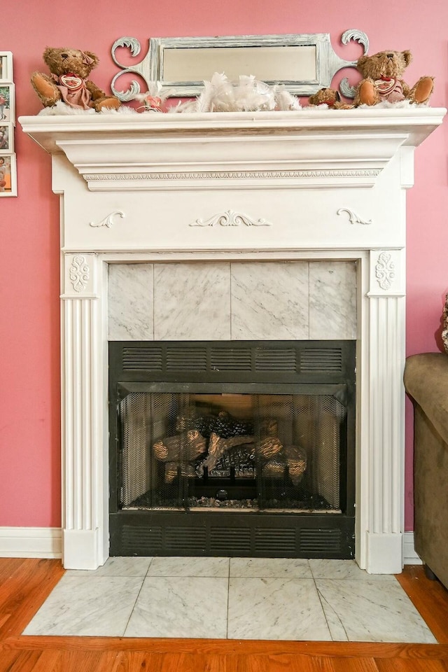 interior details featuring a tiled fireplace, baseboards, and wood finished floors
