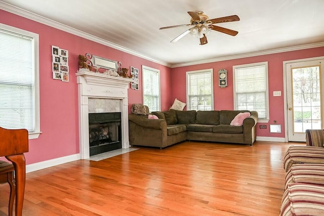 living area with a ceiling fan, a fireplace with flush hearth, light wood-style flooring, and baseboards