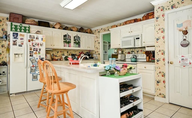 kitchen with wallpapered walls, light tile patterned floors, white appliances, and white cabinets