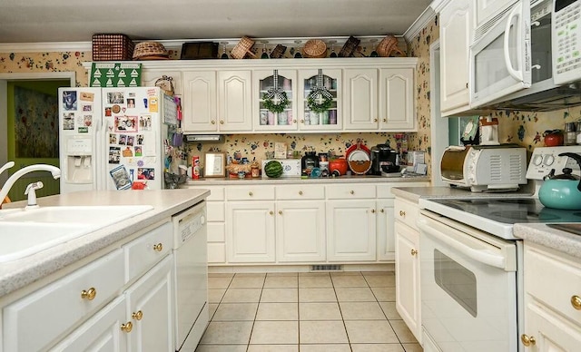 kitchen featuring a sink, light tile patterned floors, white appliances, light countertops, and wallpapered walls