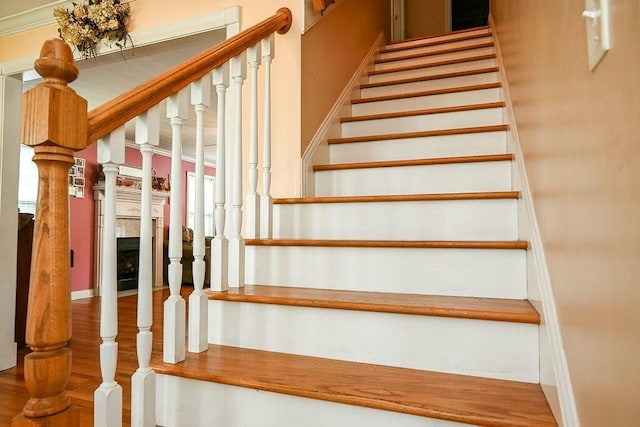 staircase with a fireplace and wood finished floors