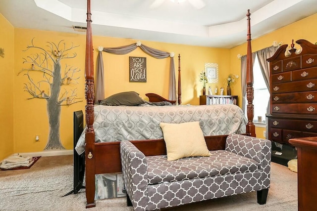 carpeted bedroom with baseboards, visible vents, and a tray ceiling