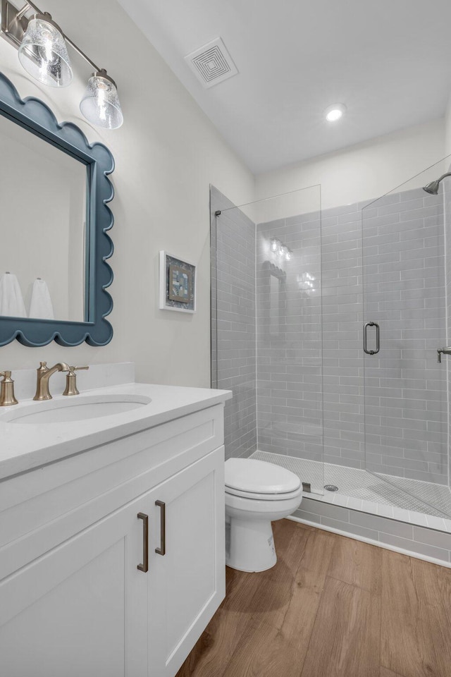 bathroom featuring a shower stall, visible vents, toilet, wood finished floors, and vanity
