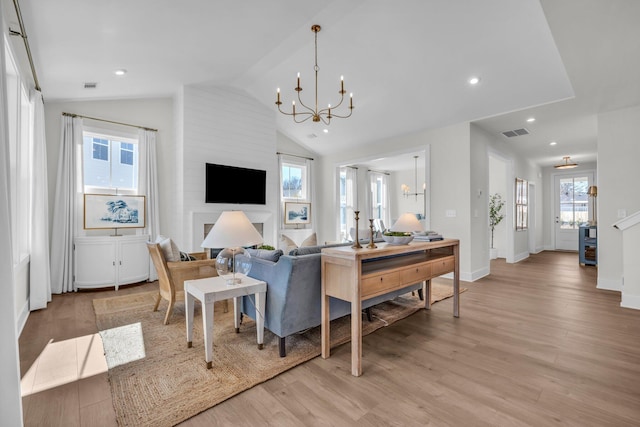 living room with visible vents, a notable chandelier, vaulted ceiling, and light wood-style floors