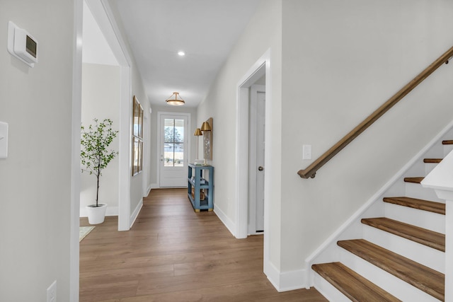 foyer featuring wood finished floors, recessed lighting, baseboards, and stairs