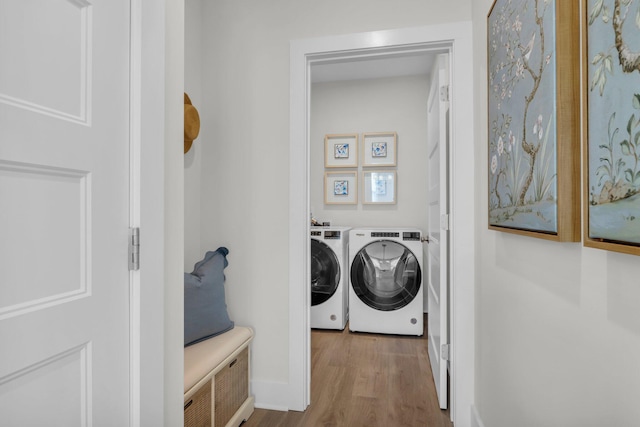 clothes washing area featuring wood finished floors, washer and clothes dryer, laundry area, and baseboards