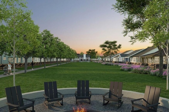 yard at dusk featuring an outdoor fire pit, a patio area, and a residential view