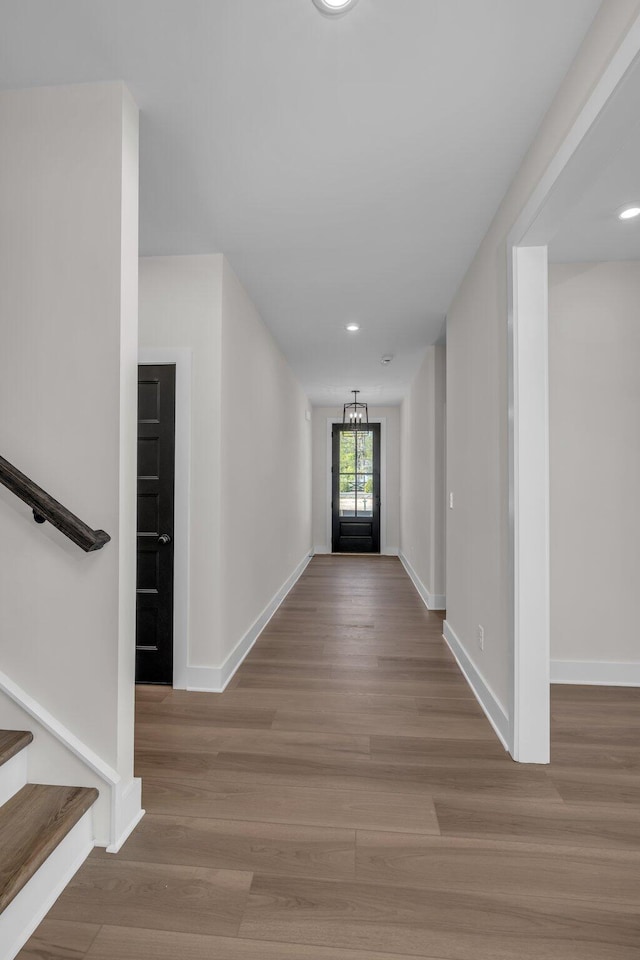 hallway featuring stairway, wood finished floors, and baseboards