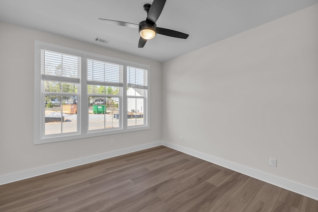 spare room with baseboards, visible vents, wood finished floors, and ceiling fan