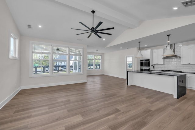 kitchen with dark countertops, open floor plan, visible vents, and wall chimney exhaust hood