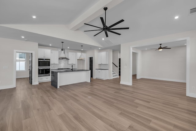 unfurnished living room with ceiling fan, recessed lighting, vaulted ceiling with beams, and light wood-style floors