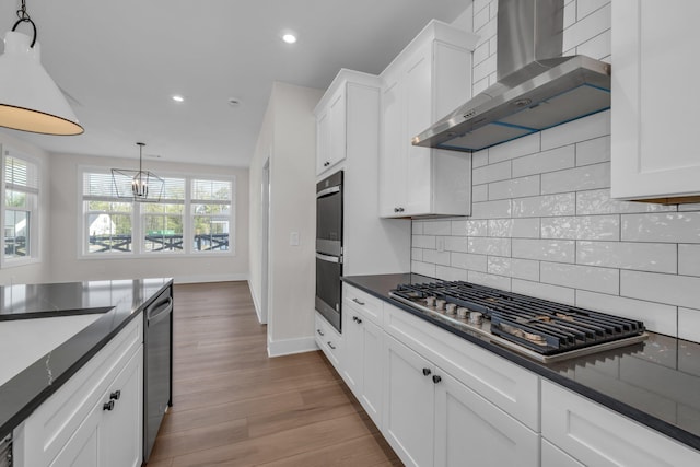 kitchen with decorative backsplash, appliances with stainless steel finishes, baseboards, recessed lighting, and wall chimney exhaust hood