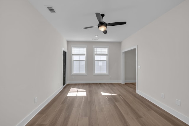 unfurnished room featuring wood finished floors, a ceiling fan, visible vents, and baseboards