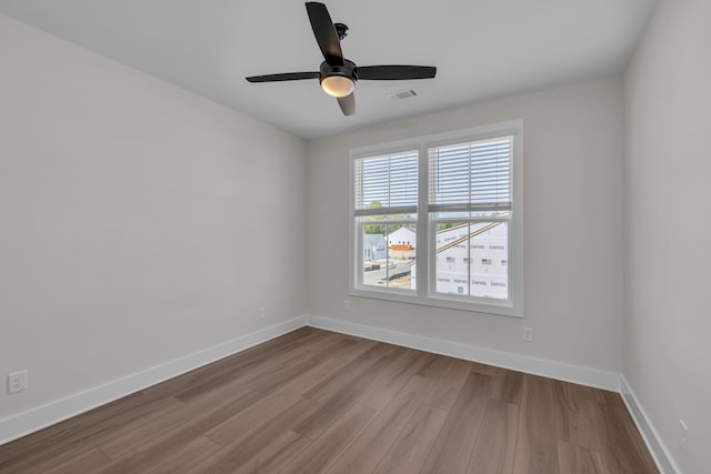 empty room with visible vents, wood finished floors, and baseboards