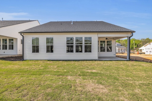 back of property with a patio, a ceiling fan, a yard, and roof with shingles