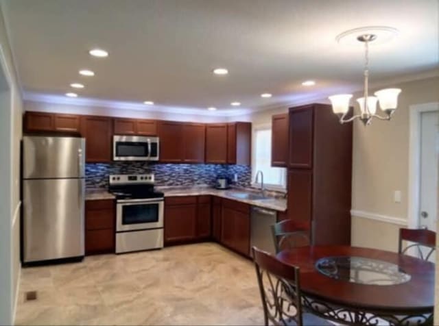 kitchen with crown molding, decorative backsplash, an inviting chandelier, light countertops, and appliances with stainless steel finishes