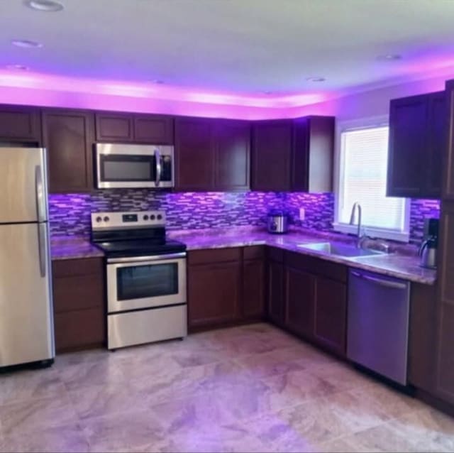 kitchen featuring stainless steel appliances, dark countertops, a sink, and tasteful backsplash