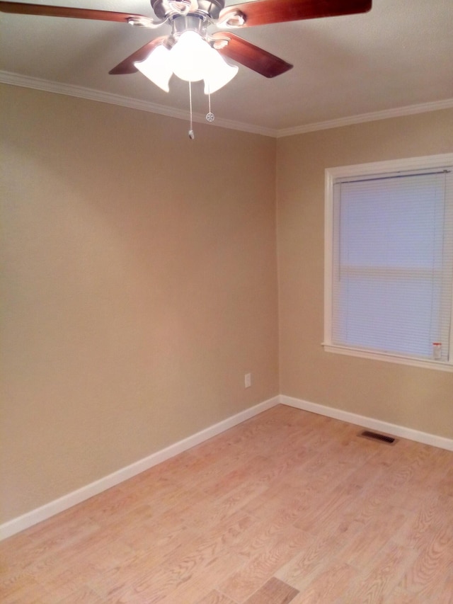 empty room featuring ceiling fan, light wood-style flooring, baseboards, visible vents, and ornamental molding