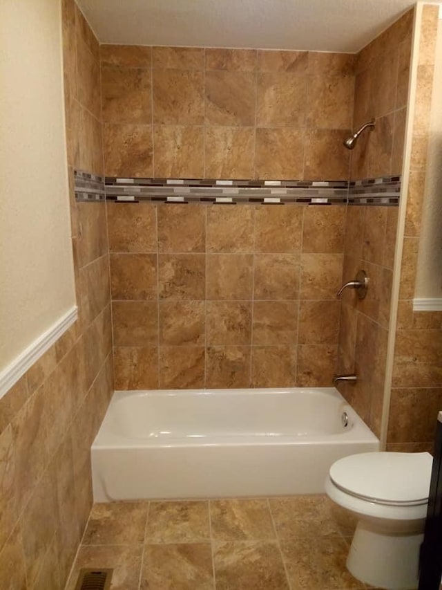 full bath featuring shower / bath combination, toilet, and tile walls