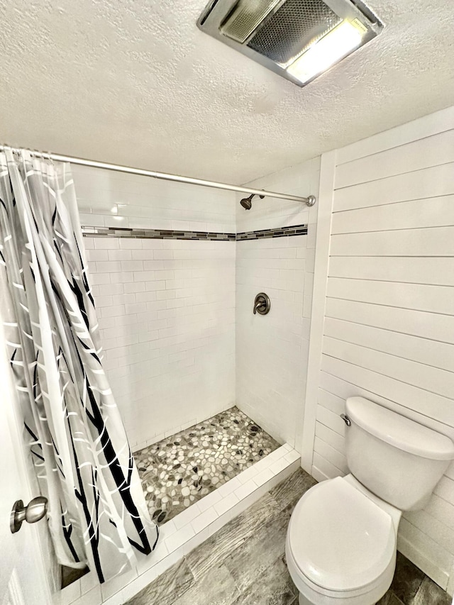 full bathroom featuring toilet, a textured ceiling, visible vents, and tiled shower