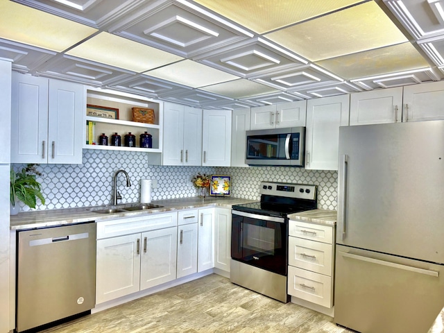 kitchen featuring stainless steel appliances, backsplash, light wood-style flooring, and a sink