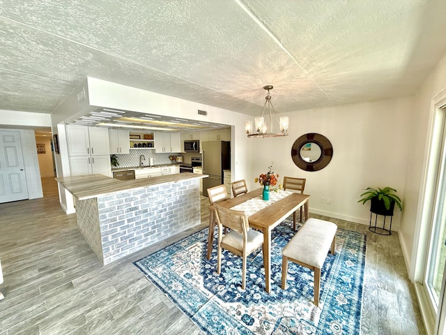 dining room with visible vents, a textured ceiling, a chandelier, and light wood finished floors