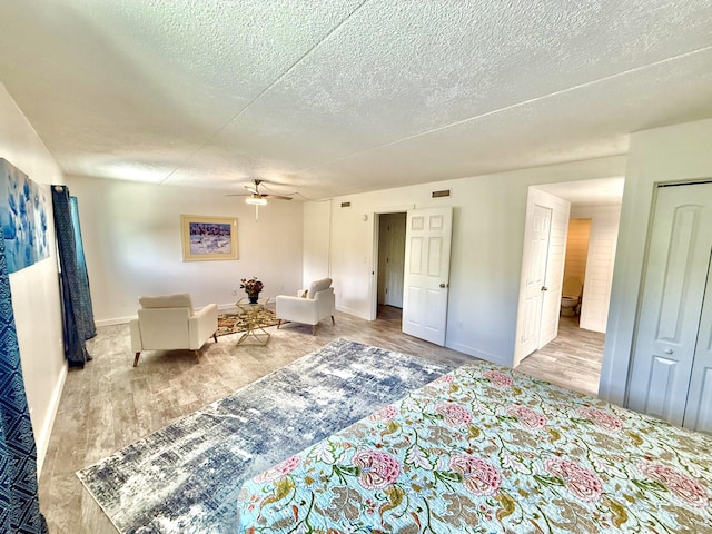 interior space with a textured ceiling, wood finished floors, a ceiling fan, and baseboards