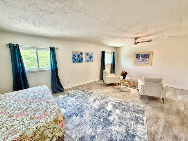 bedroom with baseboards, wood finished floors, ceiling fan, and a textured ceiling