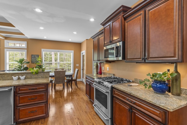 kitchen with recessed lighting, light stone countertops, stainless steel appliances, and light wood finished floors