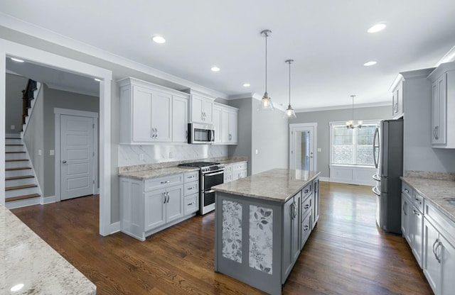 8520 Winter Refuge Way, Ooltewah, TN 37363 - kitchen with light stone countertops, appliances with stainless steel finishes, a kitchen island, ornamental molding, and backsplash