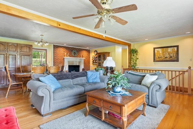 living room with light wood-style floors, ornamental molding, and ceiling fan with notable chandelier