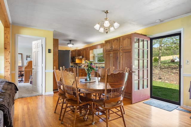 dining space with an inviting chandelier, light wood-style flooring, crown molding, and visible vents