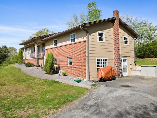 view of side of home featuring brick siding, a yard, and a chimney