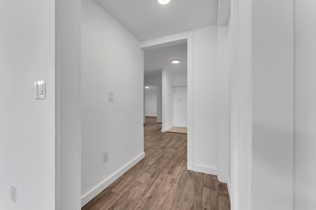 corridor featuring baseboards and wood finished floors