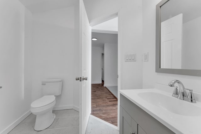 half bathroom with baseboards, vanity, toilet, and marble finish floor