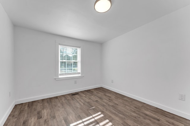 empty room featuring baseboards, visible vents, and wood finished floors