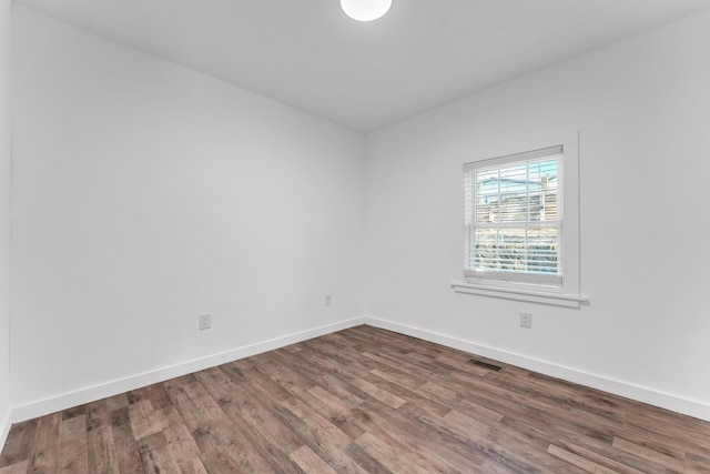 empty room featuring baseboards, wood finished floors, and visible vents