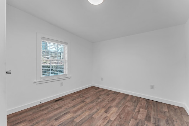 unfurnished room featuring baseboards, wood finished floors, and visible vents