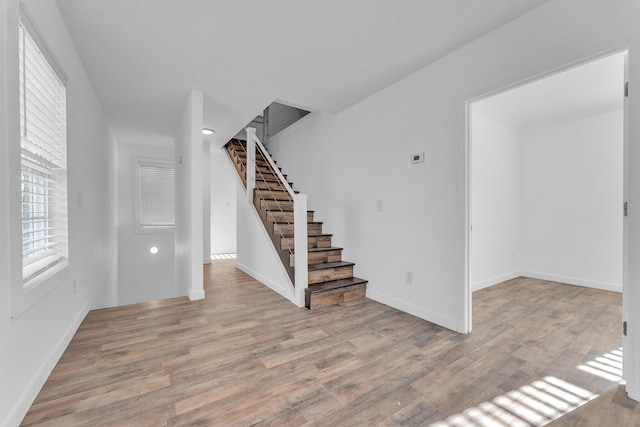 interior space with light wood-type flooring, stairs, and baseboards
