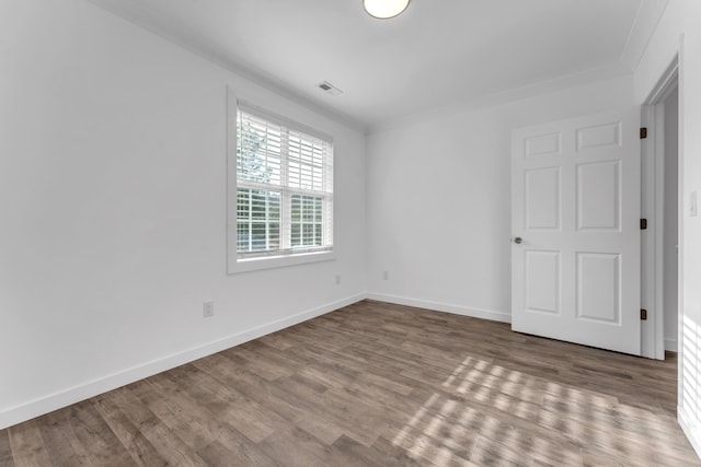 unfurnished bedroom featuring visible vents, ornamental molding, baseboards, and wood finished floors