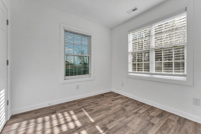 spare room with baseboards, wood finished floors, and visible vents