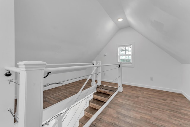 staircase featuring baseboards, vaulted ceiling, and wood finished floors