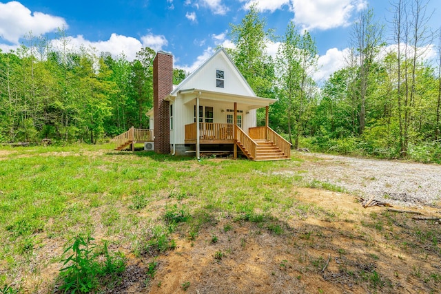 back of property featuring a porch, stairway, and a chimney