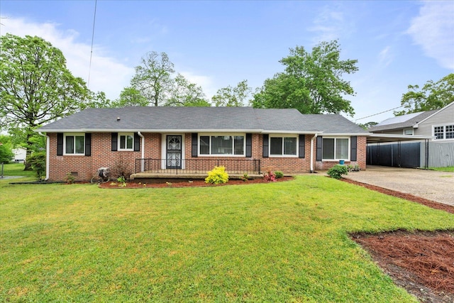 ranch-style home featuring fence, a front yard, an attached carport, brick siding, and concrete driveway