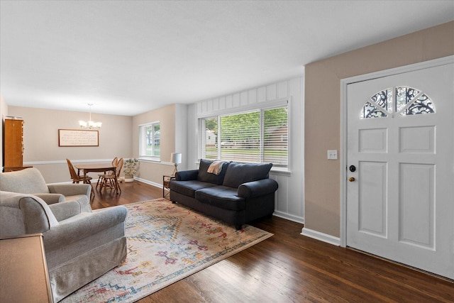 living room featuring baseboards, an inviting chandelier, and dark wood-style floors