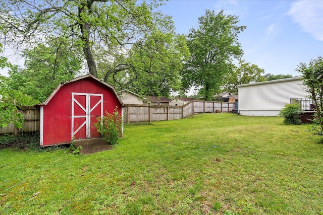 view of yard with an outdoor structure, a fenced backyard, and a storage unit