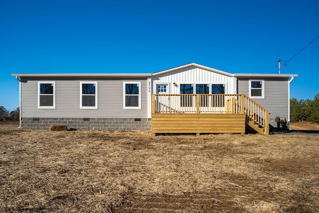 rear view of house with a deck, board and batten siding, and crawl space
