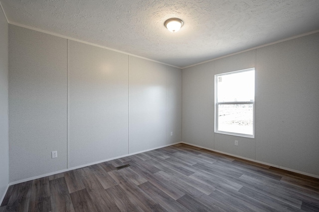 empty room with baseboards, ornamental molding, a textured ceiling, and wood finished floors